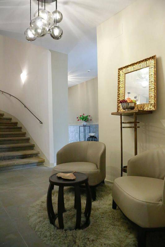 Eleganter Eingangsbereich mit geschwungener Treppe, bequemen Sesseln und dekorativem Spiegel.