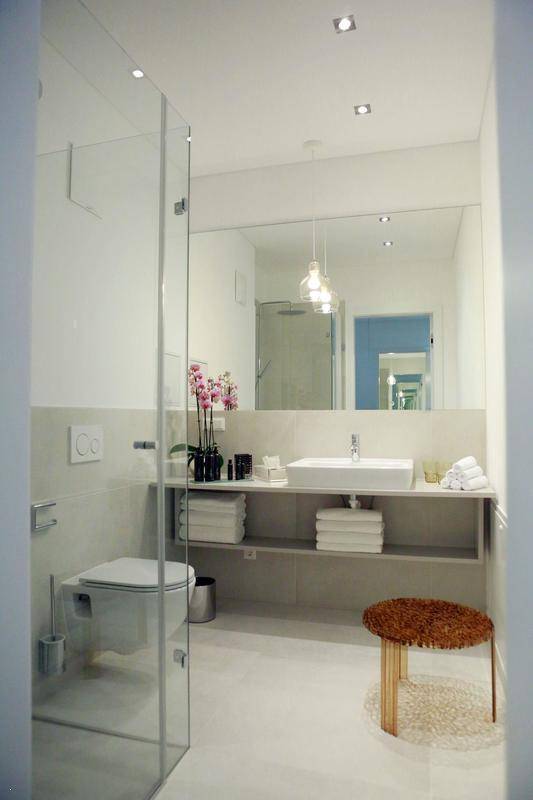 Modernes Badezimmer mit begehbarer Dusche, großem Spiegel und minimalistischem Design.