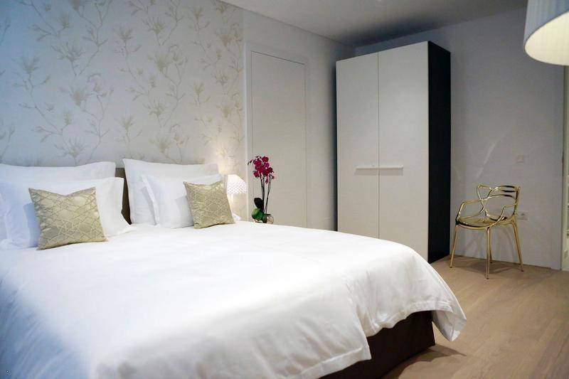 Helles Schlafzimmer mit Doppelbett, floraler Tapete und modernem Kleiderschrank.