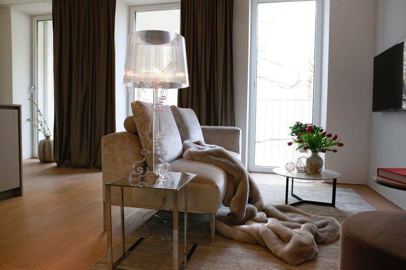 Gemütliches Wohnzimmer mit beigem Sofa, eleganter Stehlampe und großen Fenstern.