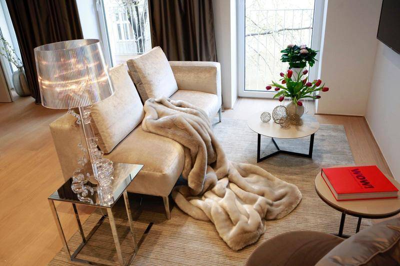 Helles Wohnzimmer mit beigem Sofa, Couchtisch und bodentiefen Fenstern.