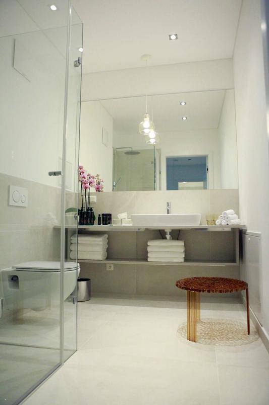 Modernes Badezimmer mit begehbarer Dusche, großem Spiegel und minimalistischem Design.