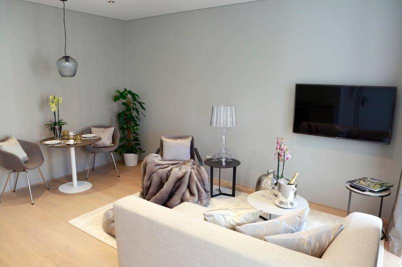 Offener Wohn-Essbereich mit Wandfernseher, bequemer Couch und kleinem Esstisch.