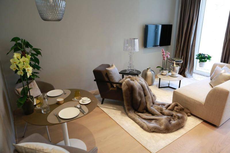 Heller Wohn-Essbereich mit gedecktem Tisch, bequemer Couch und Wandfernseher.