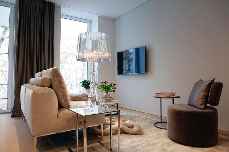 Modernes Wohnzimmer mit beigem Sofa, eleganter Stehlampe und Wandfernseher.