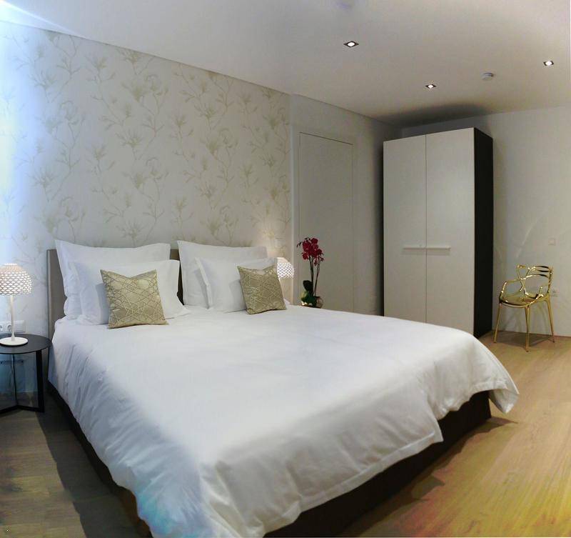 Modernes Schlafzimmer mit Doppelbett, floraler Tapete und Holzboden, ausgestattet mit einem Kleiderschrank.