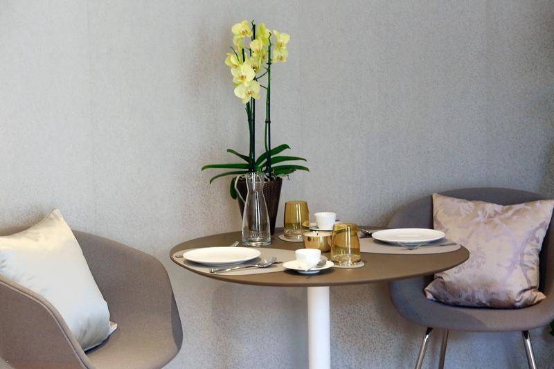 Kleiner Essbereich mit modernem runden Tisch und zwei Stühlen, dekoriert mit einer gelben Orchidee.