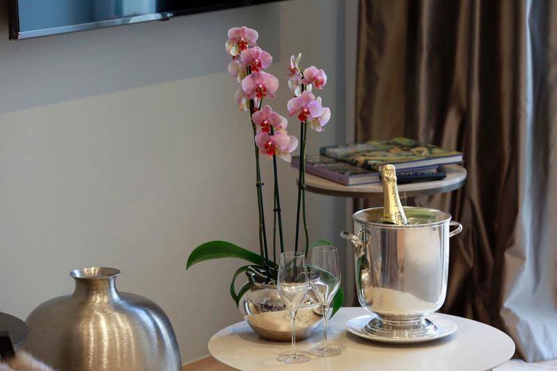 Detailaufnahme eines Beistelltisches im Wohnzimmer mit Orchidee, Champagnerkühler und Weingläsern.