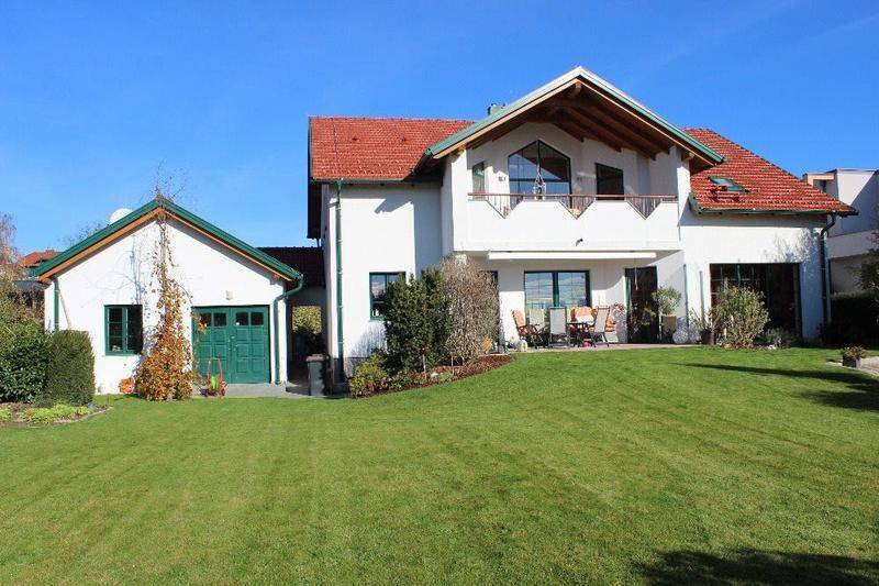 Attraktives Einfamilienhaus mit rotem Ziegeldach, großem Garten und separatem Garagengebäude.