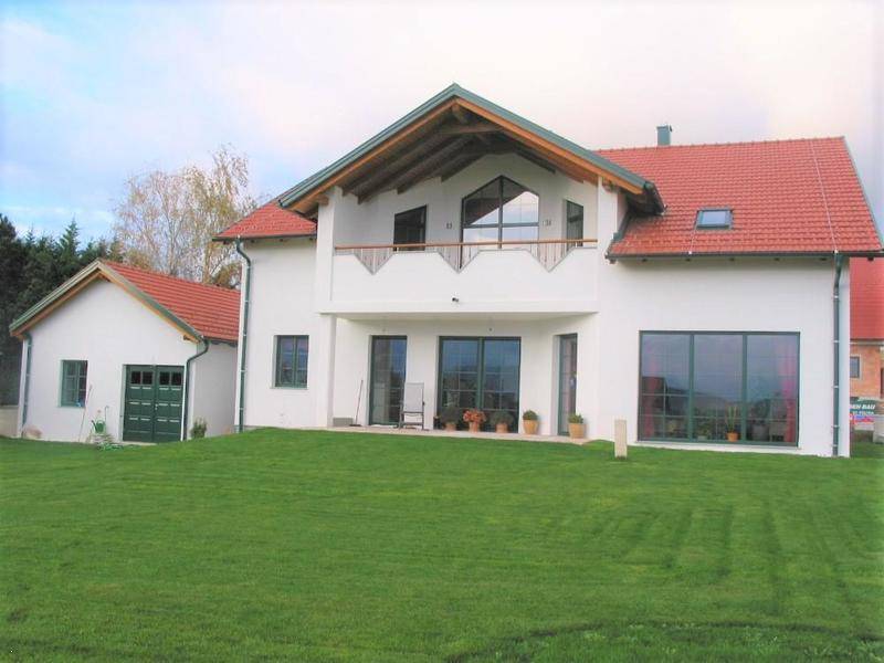 Geräumiges Einfamilienhaus mit rotem Dach, großen Fenstern und weitläufigem Rasenbereich.