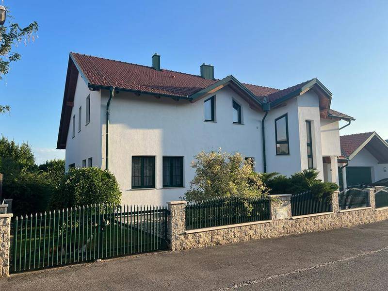Weitläufige Ansicht des Einfamilienhauses mit gepflegtem Vorgarten und stabiler Umzäunung.
