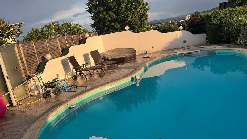 Entspannender Poolbereich mit Liegestühlen, Whirlpool und dekorativer Wandgestaltung im Garten.