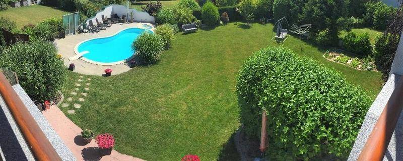 Weitläufiger Gartenbereich mit großem Pool, Liegewiese und verschiedenen Sitzgelegenheiten.