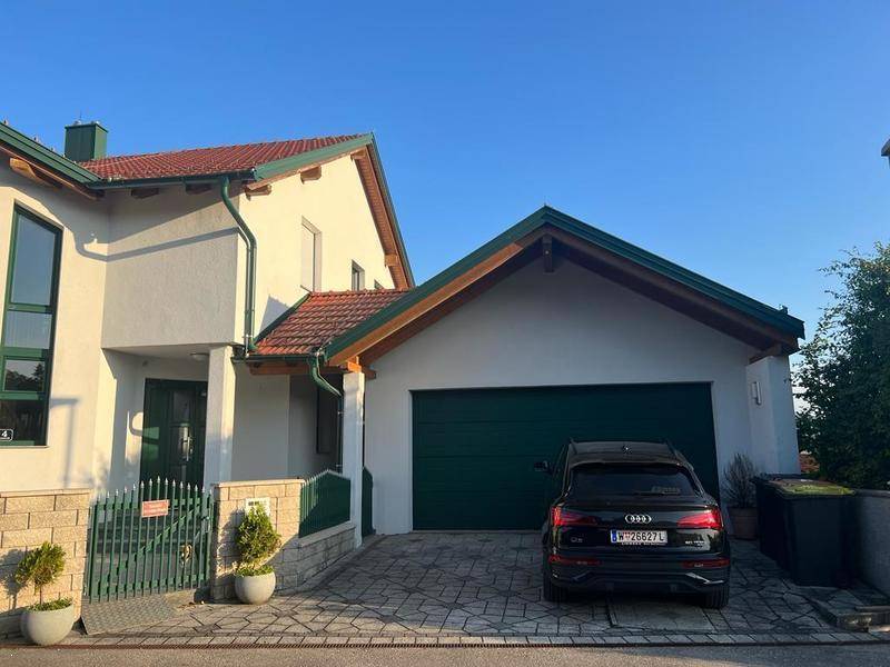 Einfahrt zum Haus mit Doppelgarage und gepflastertem Stellplatz für Fahrzeuge.