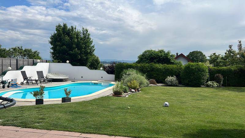 Weitläufiger Garten mit großem Pool, Liegewiese und umzäuntem Bereich unter bewölktem Himmel.