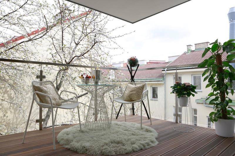 Gemütlicher Balkon mit Sitzgelegenheiten und Blick auf die umliegenden Gebäude und Bäume.