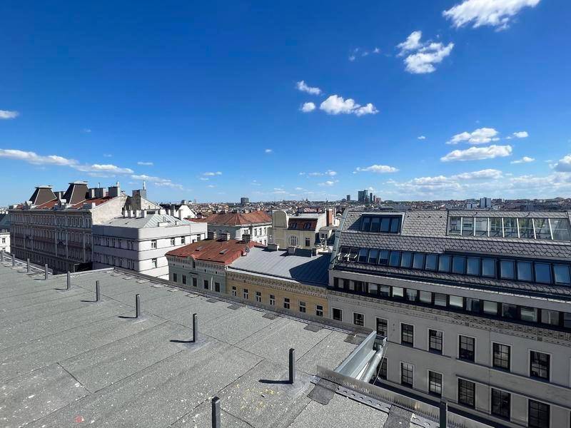 Weitläufiger Blick über die Dächer der Stadt unter blauem Himmel mit einigen Wolken.
