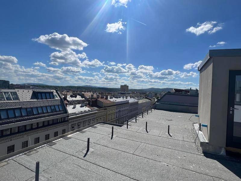 Weitläufiger Blick über die Stadt von einem Flachdach mit sonnigem Himmel.