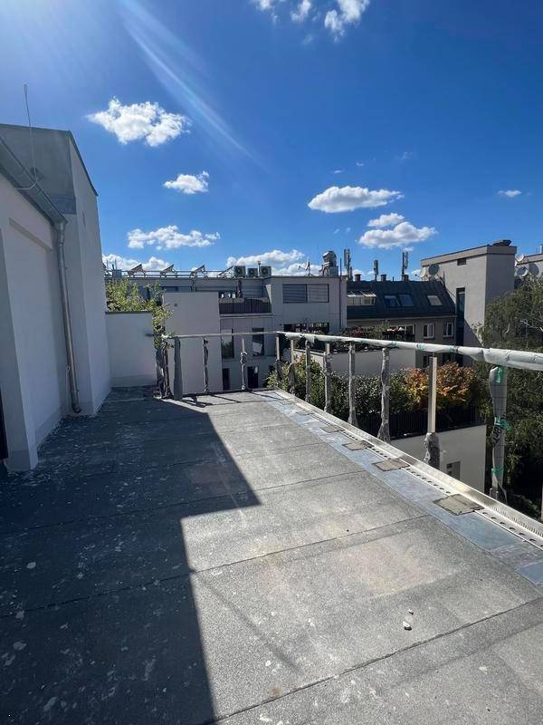 Eine im Bau befindliche Dachterrasse mit Blick auf umliegende Gebäude und den Himmel.