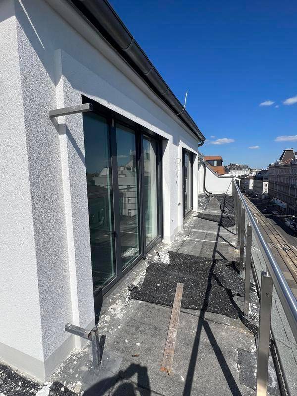 Langer Balkon mit Metallgeländer und Schiebetüren, die in den Innenraum führen.