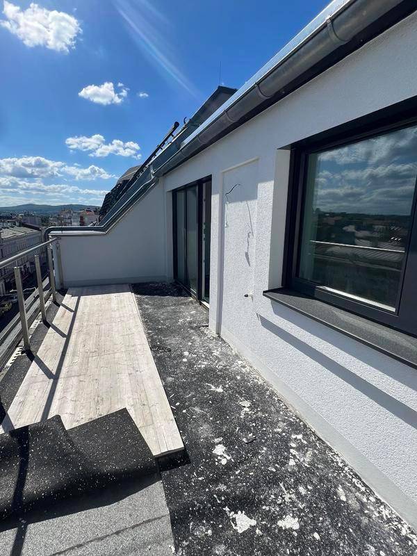 Langer Balkon mit teilweiser Holzverkleidung und Blick auf die Stadt.