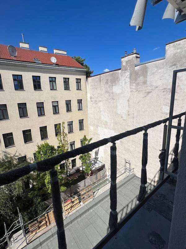 Blick von einem Balkon in einen Innenhof mit Baustellenelementen und alten Gebäudefassaden.