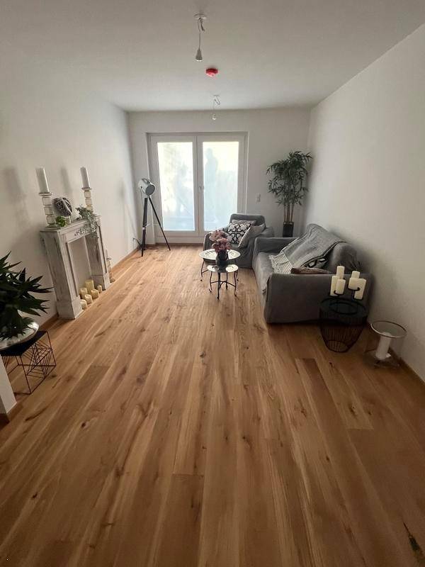 Helles Wohnzimmer mit Holzboden, einem Fenster und moderner Dekoration.