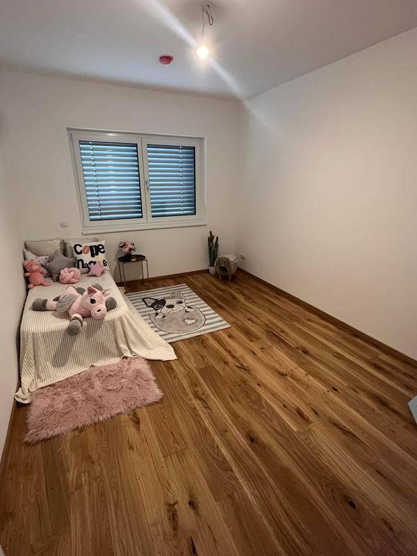 Kinderzimmer mit Holzboden, einem Fenster und kindgerechter Dekoration.
