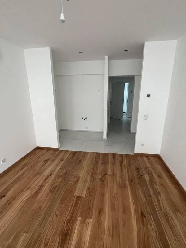 Heller Flur mit Holzboden und weiß gestrichenen Wänden, der zu weiteren Räumen führt.