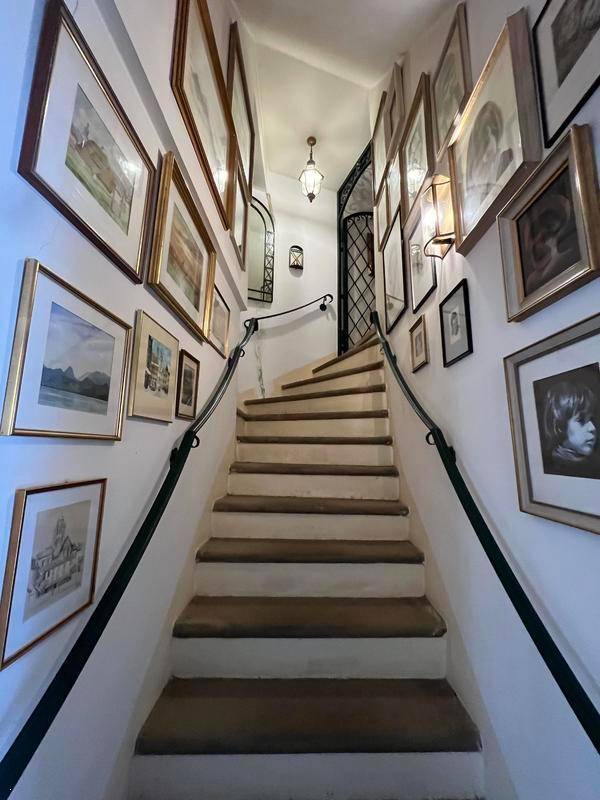Treppenhaus mit zahlreichen gerahmten Bildern an den Wänden und einem eleganten Geländer.