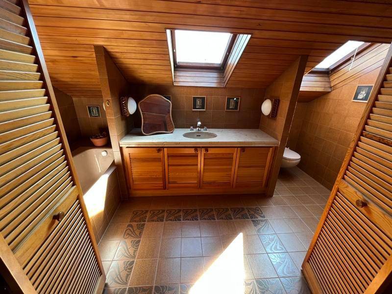 Badezimmer mit Holzverkleidung, Dachfenstern und einem Waschtisch mit Einzelwaschbecken.