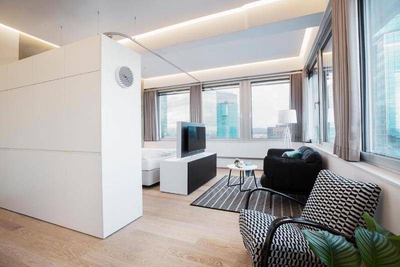 Modern eingerichteter Wohnbereich mit großen Fenstern, bequemen Möbeln und indirekter Beleuchtung.