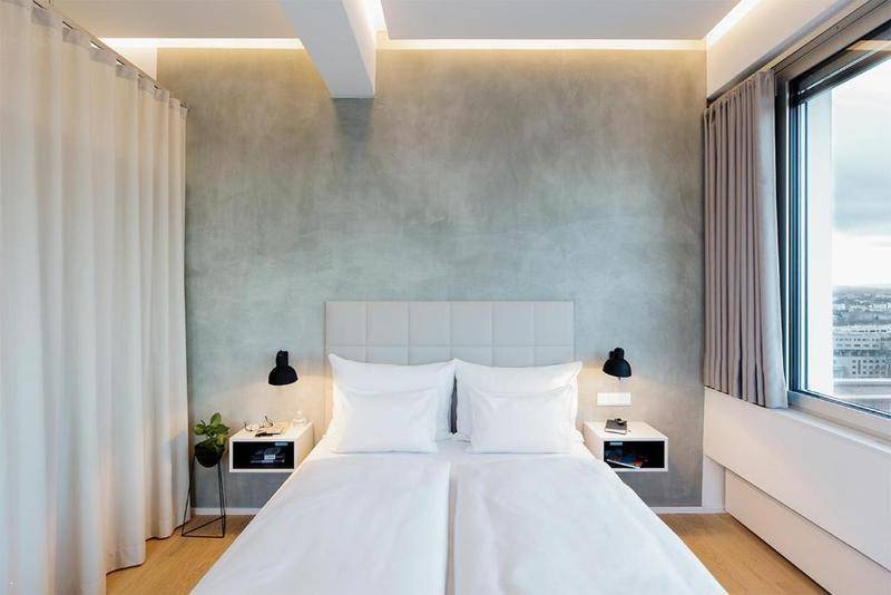 Gemütliches Schlafzimmer mit Doppelbett, Nachttischen und einer modernen grauen Akzentwand.