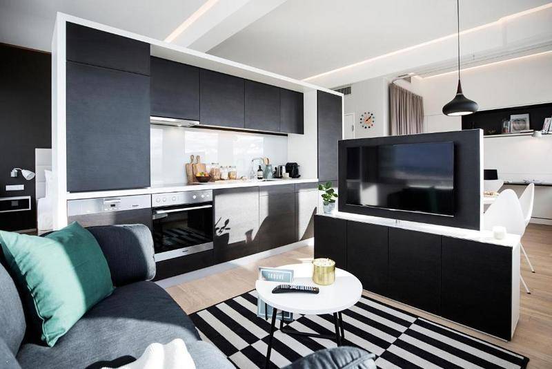 Moderne Einbauküche in Schwarz mit integrierten Geräten und offenem Übergang zum Wohnbereich.