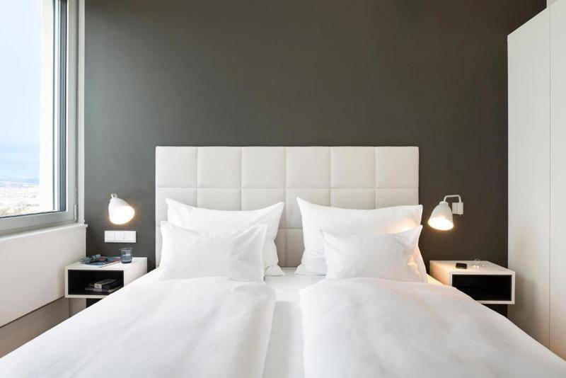 Modernes Schlafzimmer mit weißem Polsterbett, Nachttischen und dunkler Akzentwand.