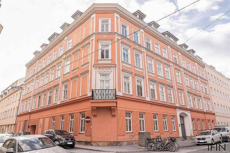 Historisches Eckgebäude mit orangeroter Fassade und kleinem französischen Balkon in städtischer Umgebung.