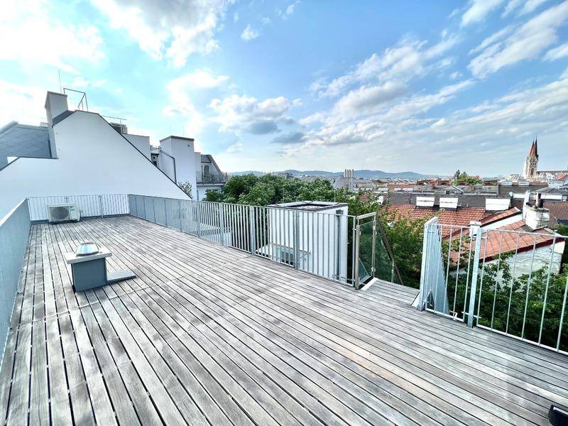Geräumige Dachterrasse mit Holzboden und weitem Blick über die Stadt.