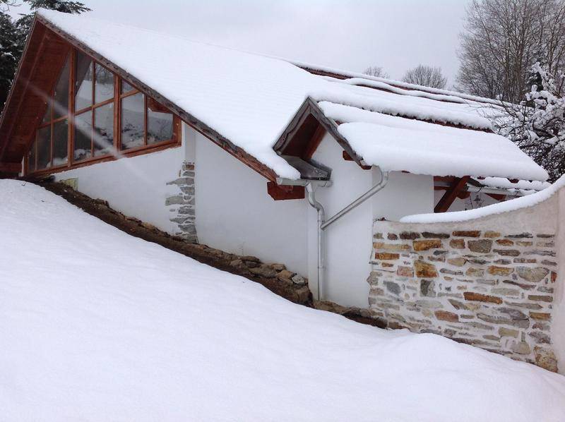 Hausfassade im Winter mit schneebedecktem Dach und Steinelementen.