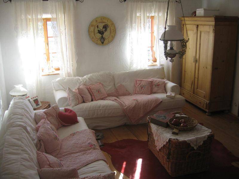 Gemütliches Wohnzimmer mit weißen Sofas, Holzboden und traditionellem Kleiderschrank.