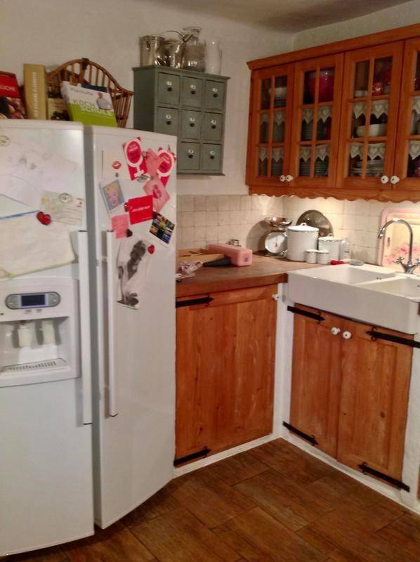 Rustikale Küche mit großem Kühlschrank, Holzschränken und traditionellem Spülbecken.