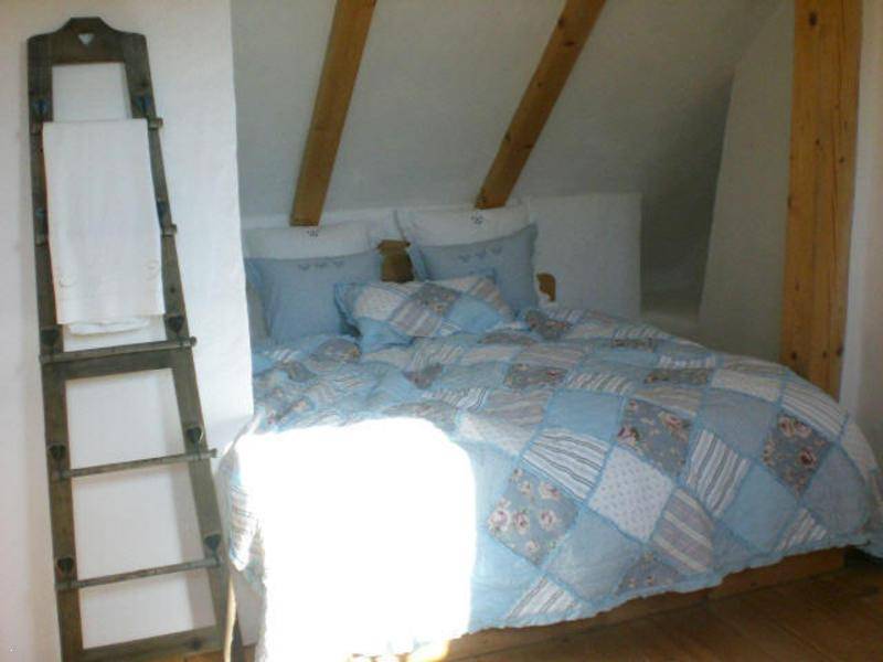 Gemütliches Schlafzimmer im Dachgeschoss mit Bett in einer Nische und Holzbalken.