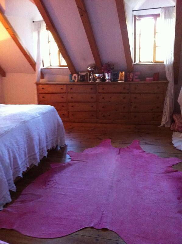 Schlafzimmer im Dachgeschoss mit Holzboden, langer Kommode und schrägen Decken.