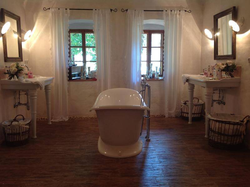Geräumiges Badezimmer mit zwei Waschtischen, freistehender Badewanne und Fenstern.