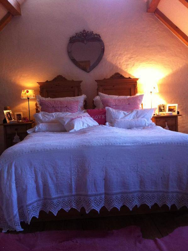 Romantisches Schlafzimmer im Dachgeschoss mit Holzbett und schrägen Decken.