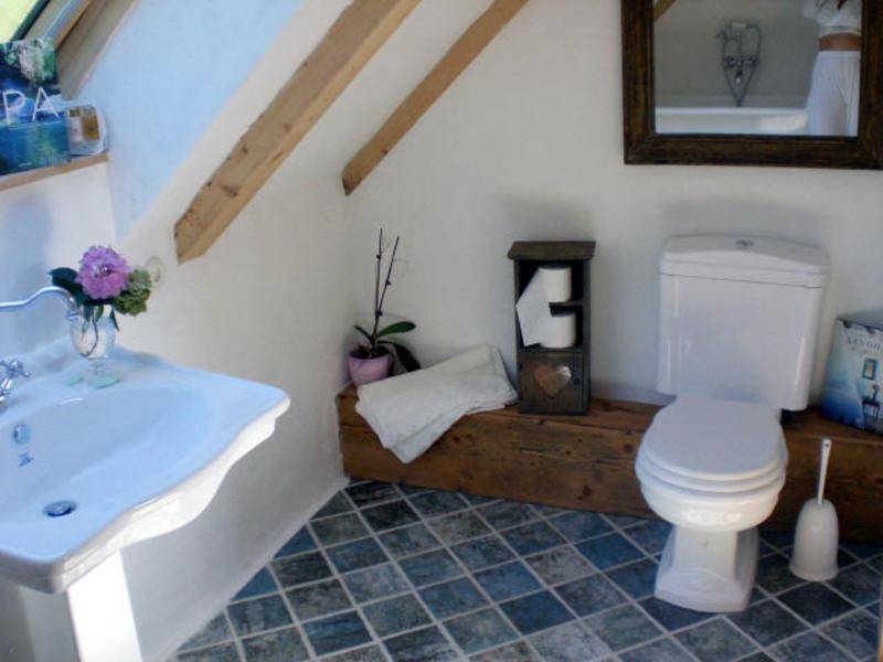 Kleines WC im Dachgeschoss mit Waschtisch, Toilette und Fliesenboden.