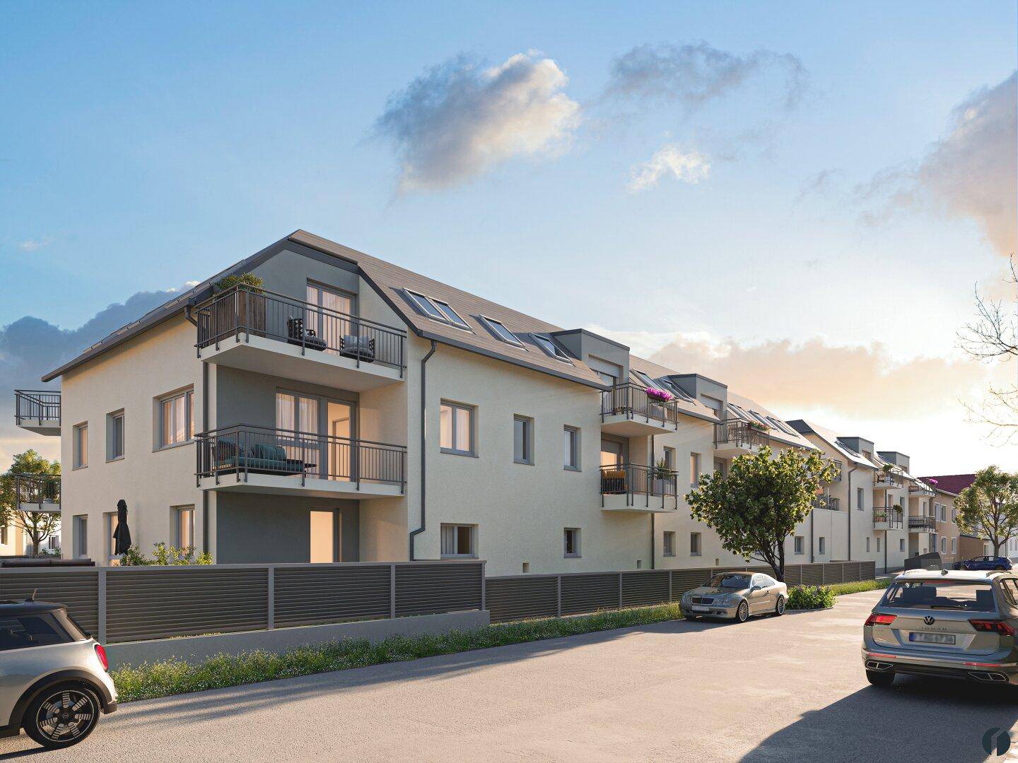 Ansicht der modernen Wohngebäude mit Balkonen und gepflegter Außenanlage bei Sonnenuntergang.