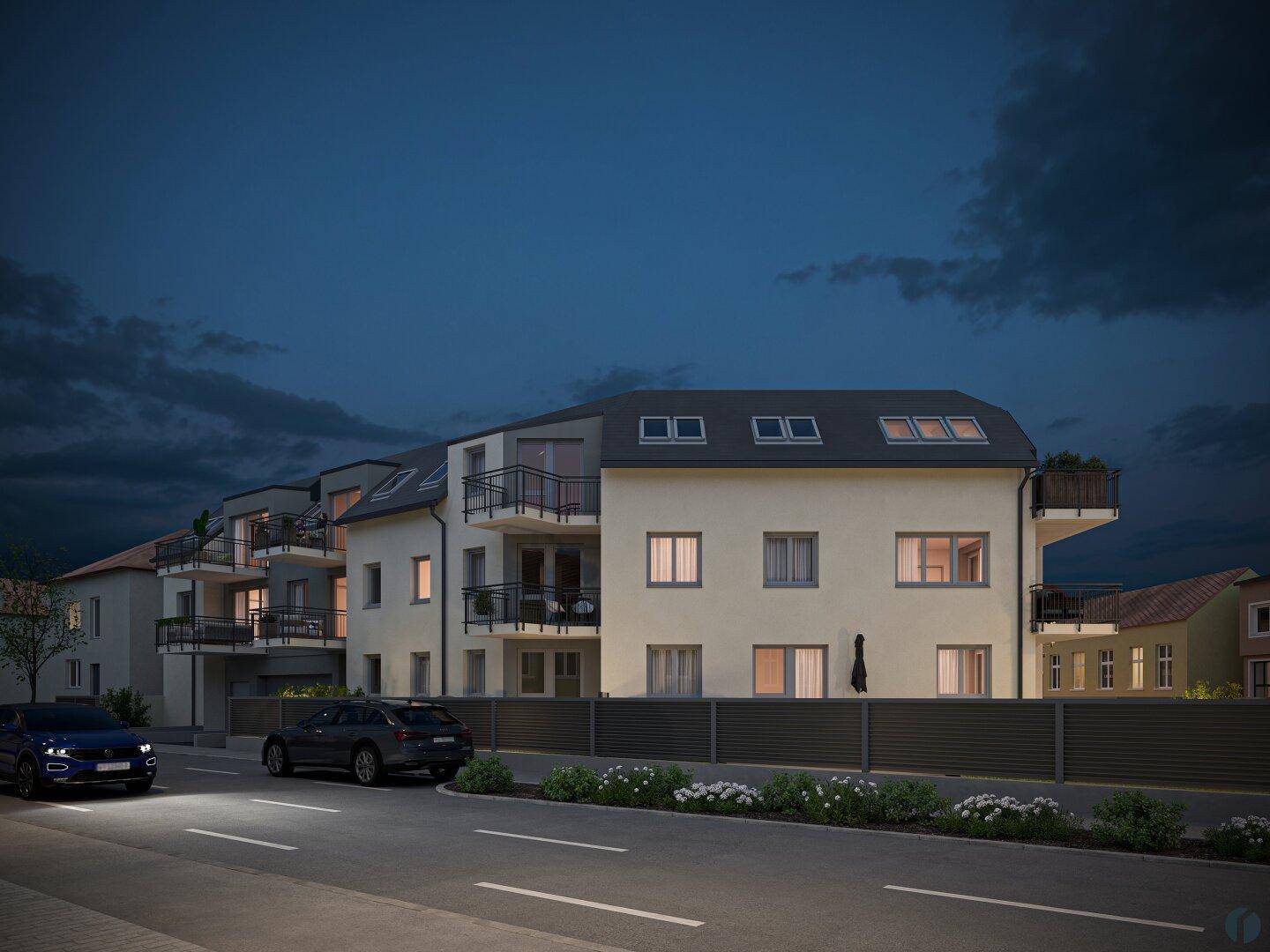 Moderne Wohnanlage bei Nacht mit beleuchteten Fenstern und geparkten Autos.