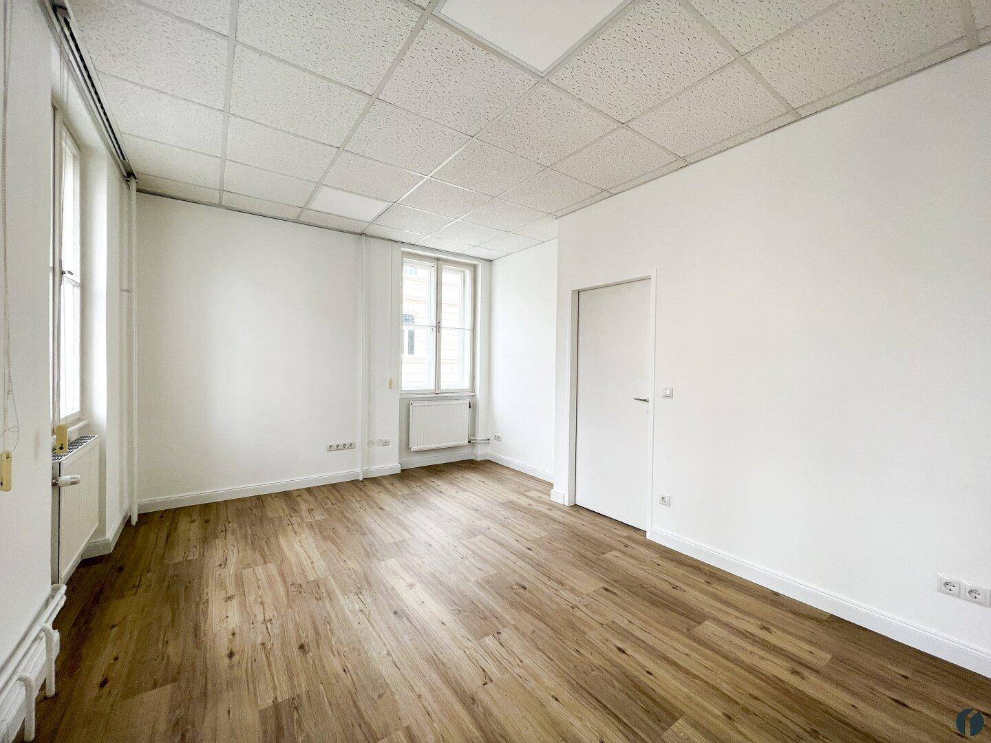 Kleineres, helles Büro mit einem Fenster, Laminatboden und weißen Wänden, vielseitig nutzbar.