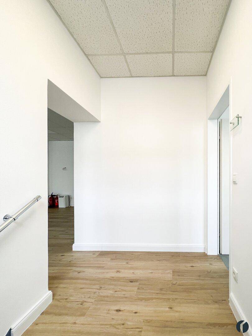 Heller Flur mit Laminatboden und weiß gestrichenen Wänden, führt zu weiteren Räumen.