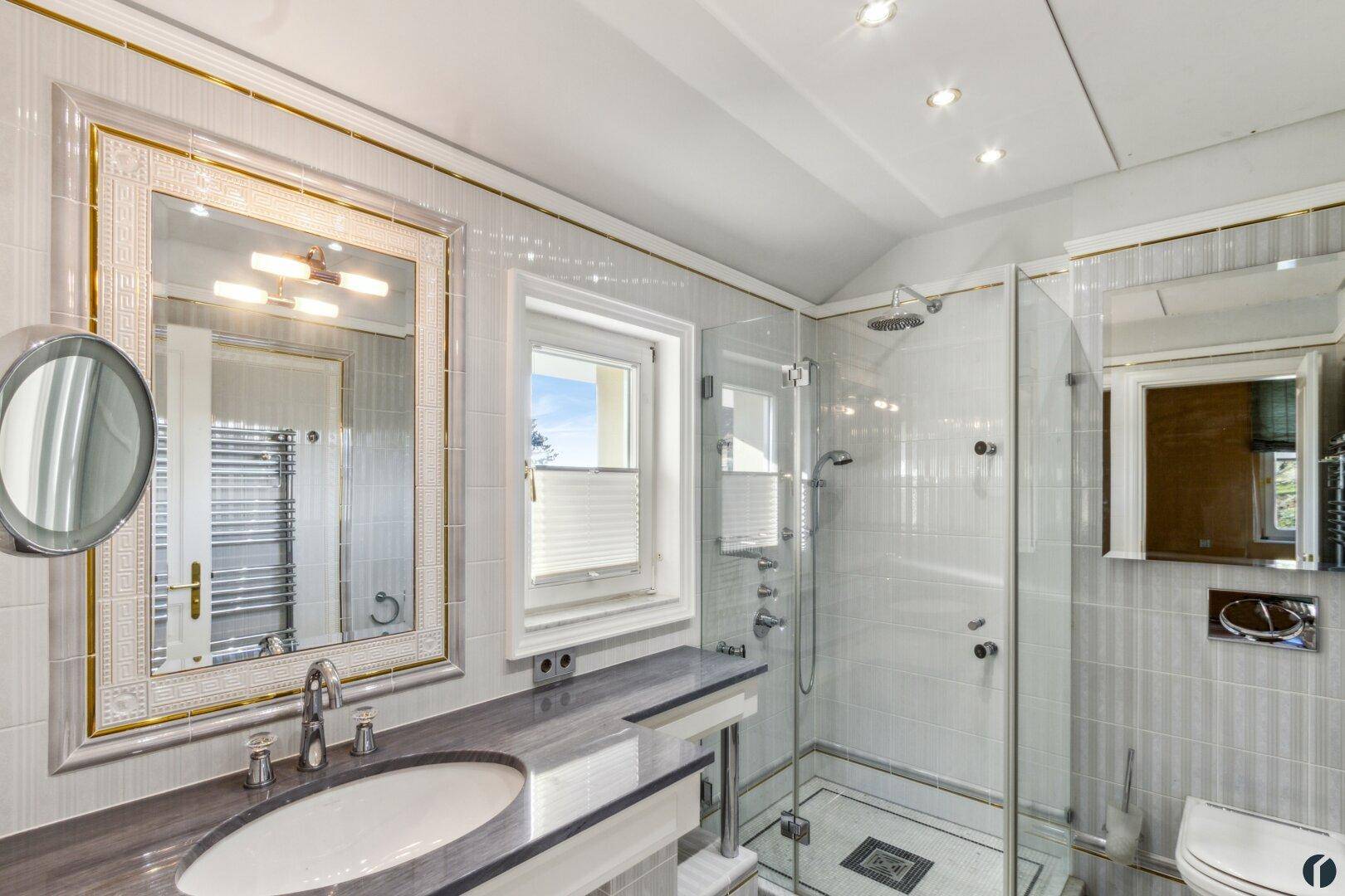 Modernes Badezimmer mit Dusche, Fenster und eleganten Fliesen in hellen Grautönen.